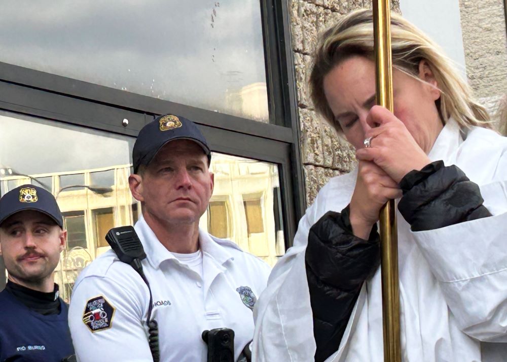 A woman bows her head in prayer during a Nov. 13 prayer vigil and eucharistic procession for immigrants outside of the Immigration and Customs Enforcement Office in Philadelphia.