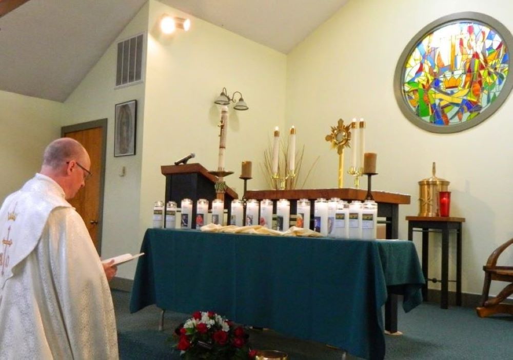 A priest blesses memorial candles lit at an Emmaus Ministry for Grieving Parents retreat held in West Virginia.
