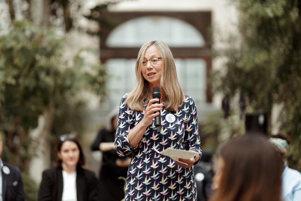 Lorna Gold stands with microphone.