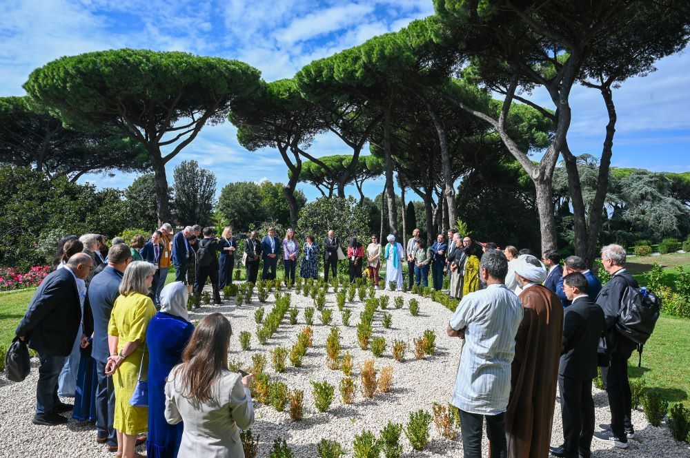 Participants in the multifaith dialogue of the Global Ethical Stocktake stand together in prayer in the Borgo Laudato Si'.