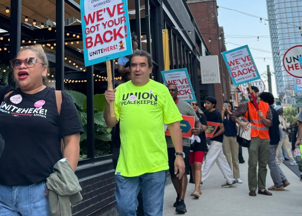 Jesus Morales walks the picket line, carrying a sign with fellow hotel workers. 
