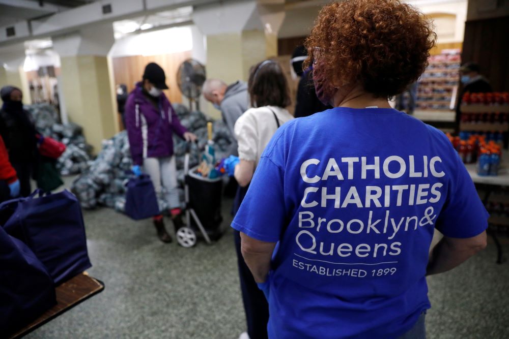 A volunteer in New York City looks on as people receive food at a food pantry.