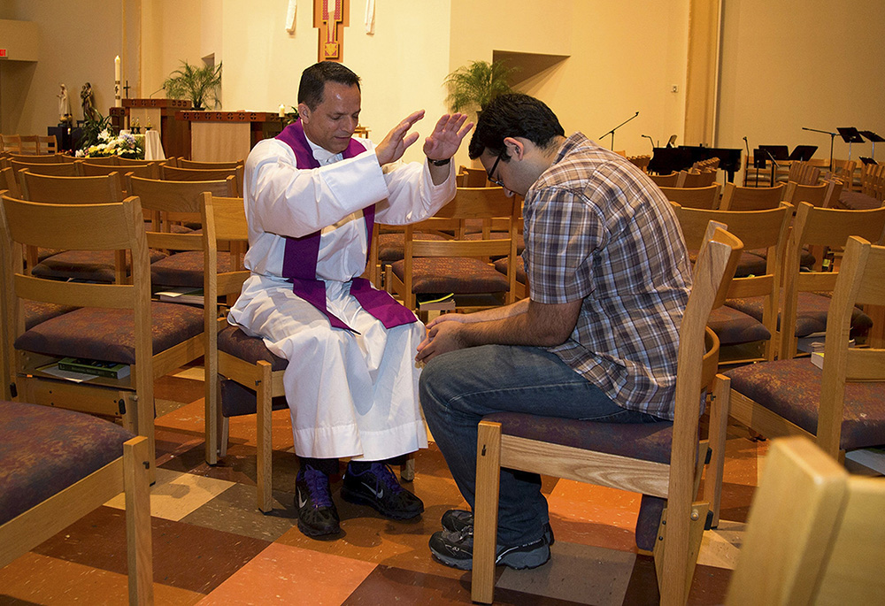 In this 2015 file photo, Paulist Fr. Jamie Baca blesses a student involved with the Fellowship of Catholic University Students at a church on the campus of the University of Texas at Austin at the University Catholic Center. (CNS/courtesy FOCUS)