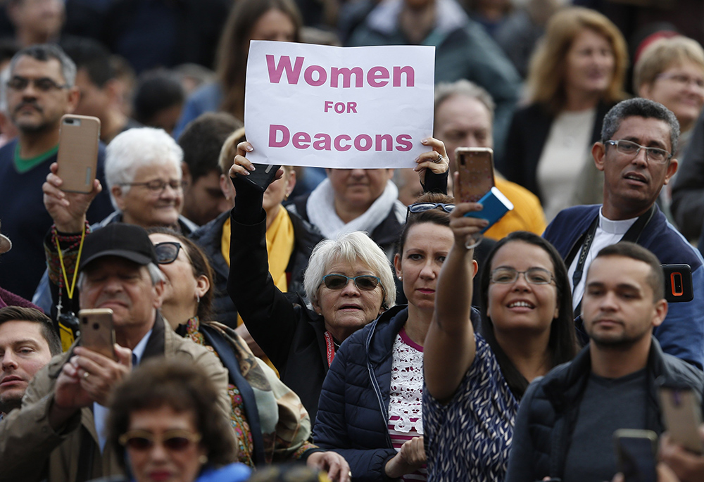 A woman holds a sign in support of women deacons as Pope Francis leads his general audience in St. Peter's Square at the Vatican Nov. 6, 2019. (CNS/Paul Haring)