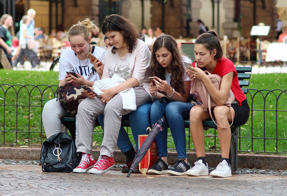A group of young women sit together while on their smartphones in this undated photo. (OSV News/Pixabay/Gary Cassel)