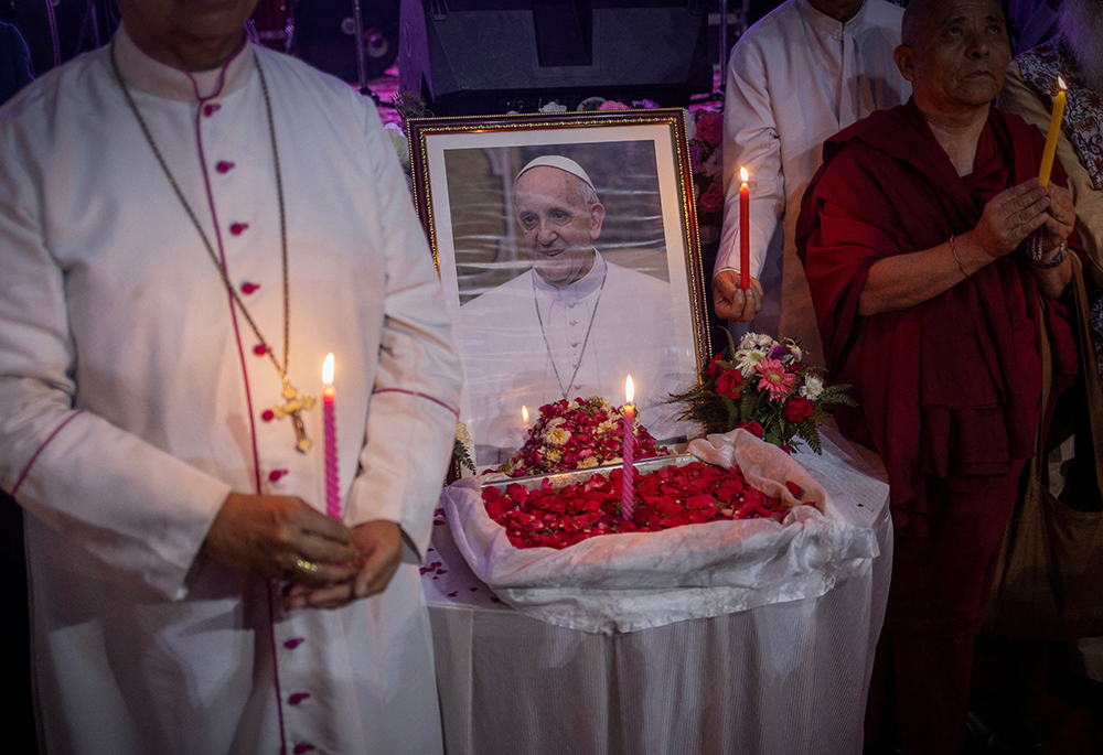 People hold candles in front of a picture of Pope Francis in New Delhi, India, April 21, 2025, after his death was announced by the Vatican. Pope Francis, formerly Argentine Cardinal Jorge Mario Bergoglio, died April 21 at age 88. (OSV News/Reuters/Adnan Abidi)