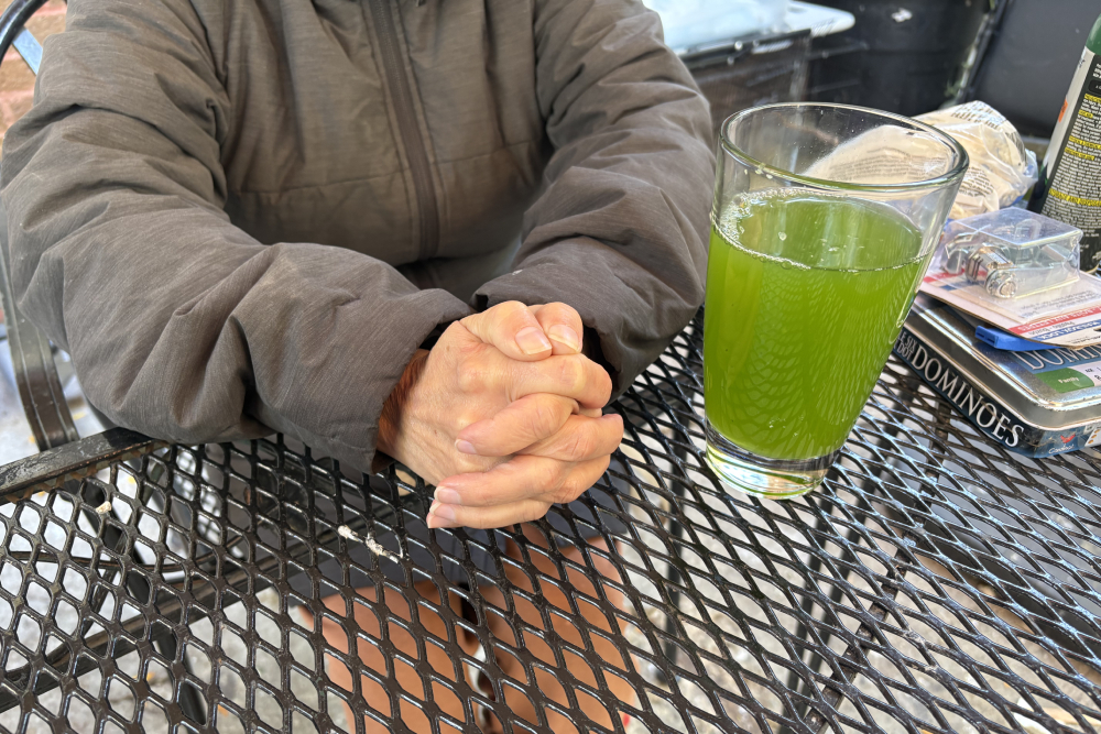 An immigrant woman being interviewed while sipping agua con pepino, espinaca y apio, or cucumber, spinach, and celery water, at a house in Pilsen, Chicago, Oct. 27, 2025. (NCR photo/Camillo Barone)
