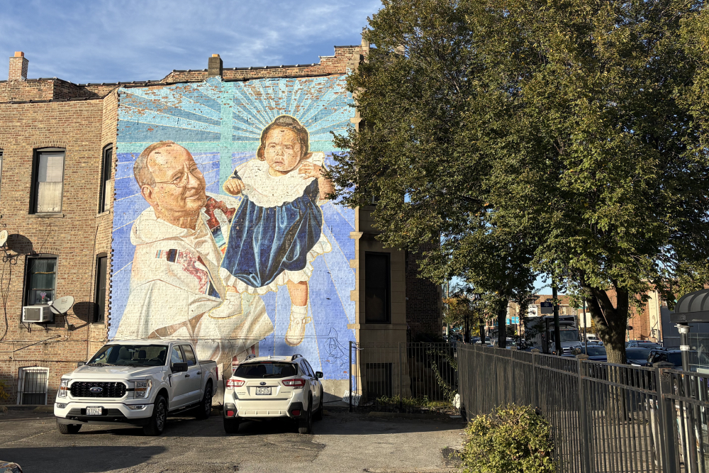 A weathered mural depicting the founder of The Resurrection Project, Dominican Fr. Charles Dahm, holding a baby in Pilsen, Chicago's Mexican neighborhood. (NCR photo/Camillo Barone)