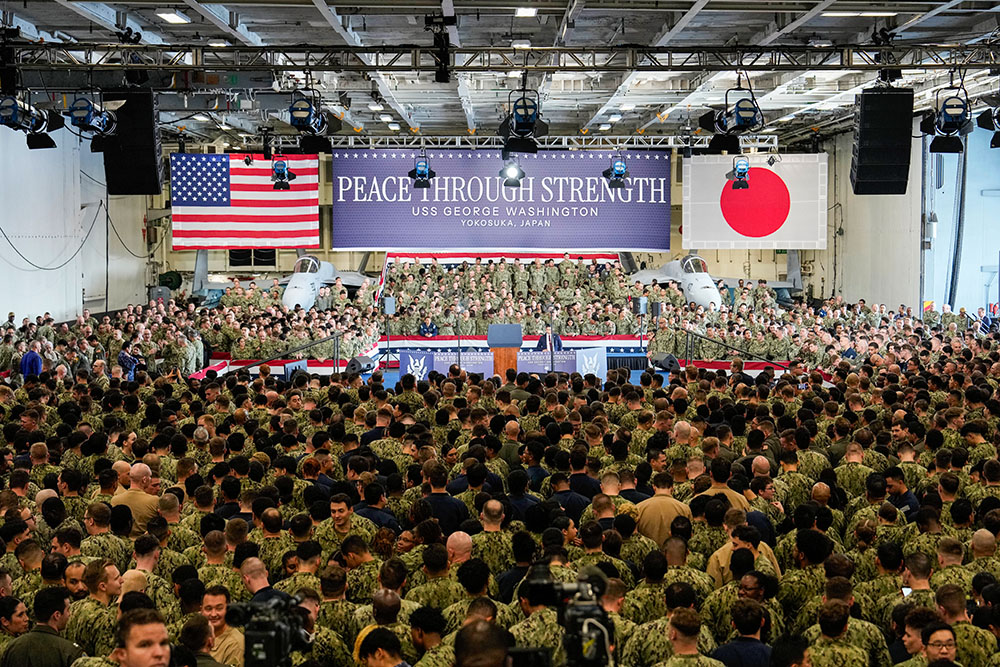 U.S. soldiers and servicemen gather around a stage setup near fighter jets as they wait for U.S. President Donald Trump's visit to the nuclear-powered aircraft carrier USS George Washington at a U.S. naval base in Yokosuka, south of Tokyo, Oct. 28, 2025. (AP/Eugene Hoshiko)