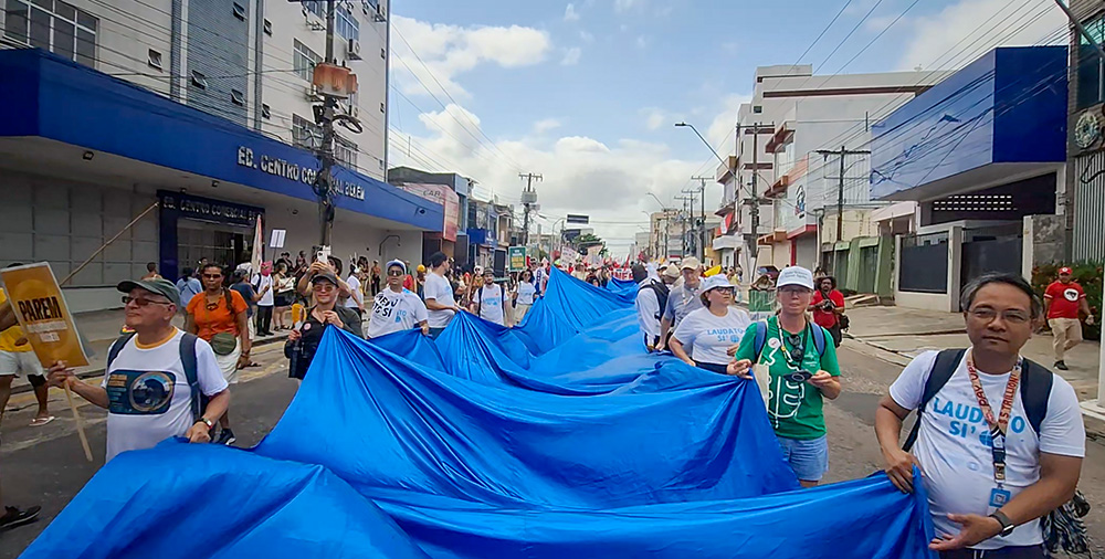 Catholics with the Laudato Si' Movement carry the "River of Hope" banner through the streets of Belém, Brazil, at the global climate march Nov. 15 during the COP30 United Nations climate change conference. (Eduardo Campos Lima)