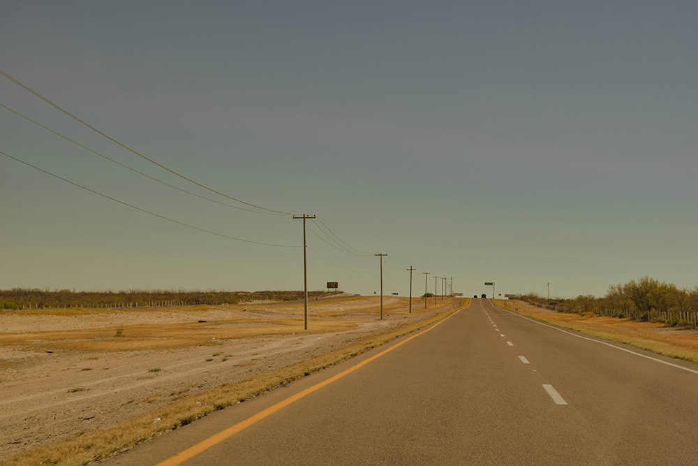 A highway lined with power lines in a brown landscape in Mexico (Unsplash/Andrea Brambila)