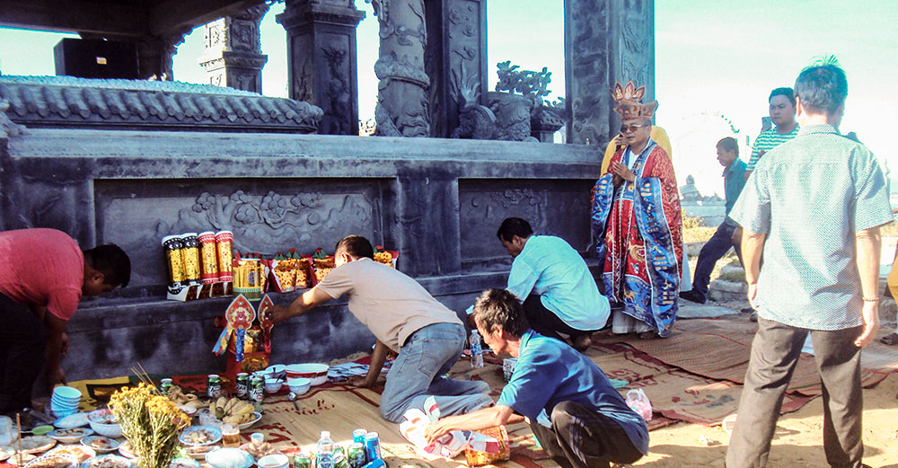 A Confucian family prepares food offerings and burns votive paper at their ancestral tomb on Oct. 21, 2025 — a common ritual to honor the deceased and invite their blessings. (Joachim Pham)