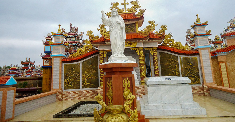 A statue of Jesus stands between the graves of Paul Van Cong Phuc's parents. His father rests to the right, while his mother, still living, regularly visits the site to pray. (Joachim Pham)