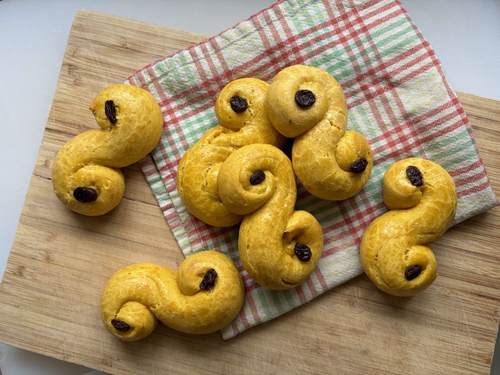Pastries called lussekatter displayed on a bread board