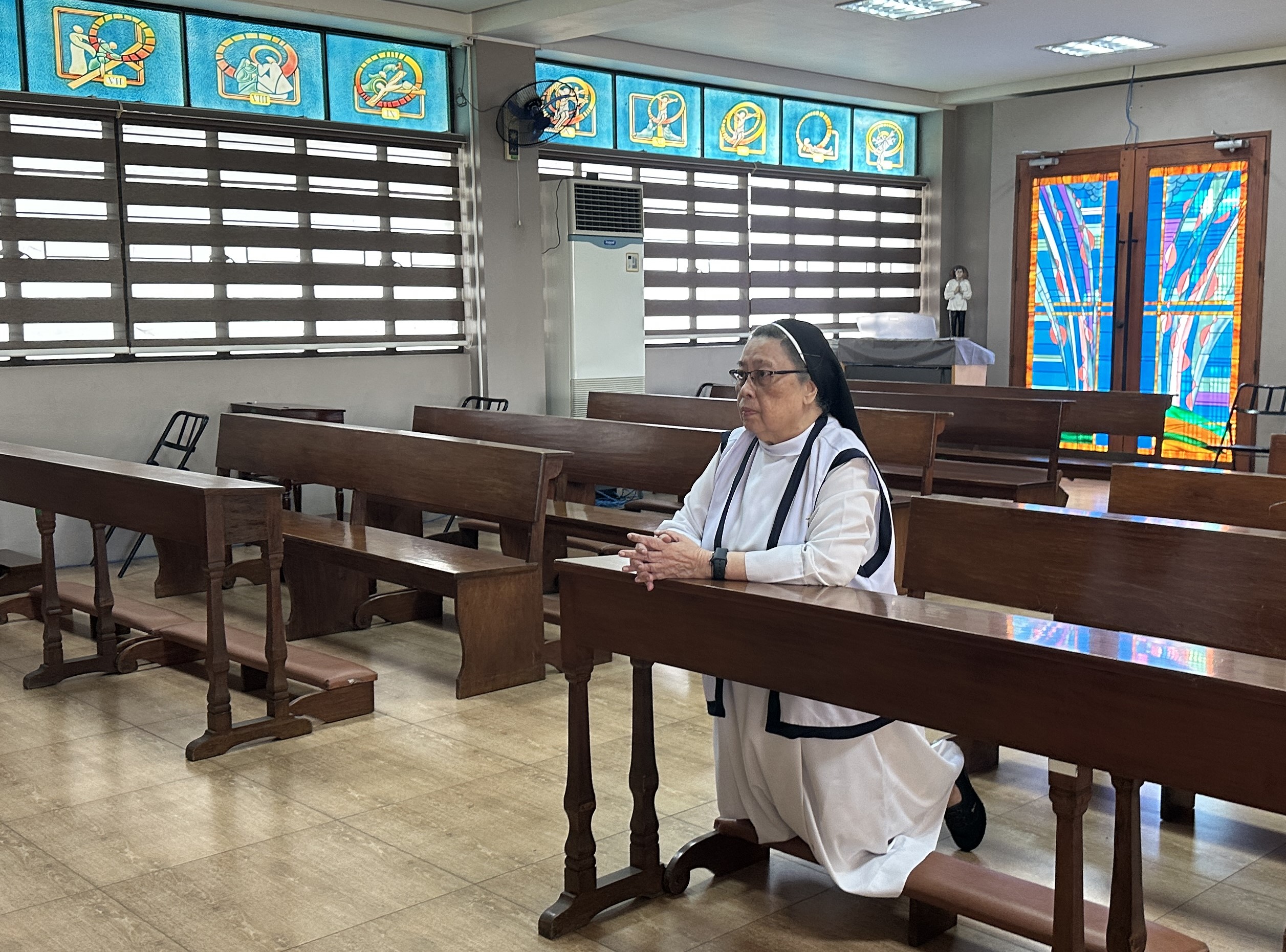 Missionary Benedictine Sr. Mary John Mananzan kneels in a chapel.