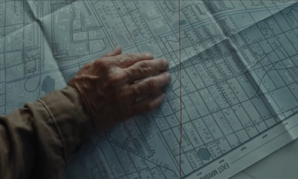 Movie still shows hand on map.