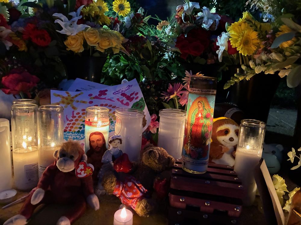 Candles, flowers and stuffed animals fill a community memorial. 