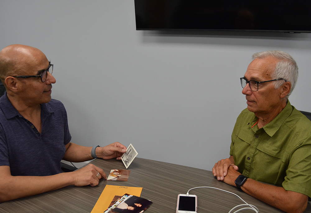 Pope Leo XIV's brother John Prevost, right, and his friend Augustinian Fr. Ray Flores, look at a photo of what Prevost guessed was the pope's 9th birthday cake and ice cream celebration at home, in the Chicago suburb of New Lenox, Illinois. (OSV News/Simone Orendain)