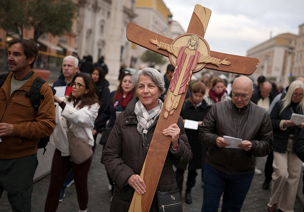 A pilgrim carries a crucifix in Rome near the Vatican's St. Peter's Square Dec. 4, 2025, after a high-level Vatican commission voted against ordaining Catholic women to serve as deacons while also supporting more study on the issue, according to a report addressed to Pope Leo XIV and released by the Vatican that day. (OSV News/Reuters/Guglielmo Mangiapane)