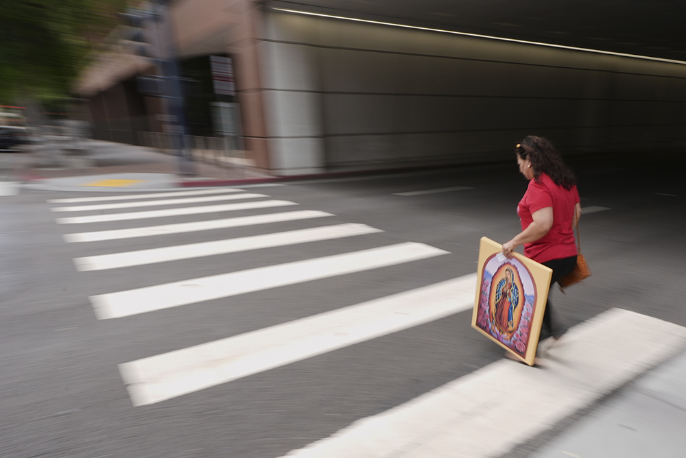 A woman carries an image of the Virgin of Guadalupe after an interfaith group led by San Diego Bishop Michael Pham entered a federal building to be present during immigration hearings June 20, 2025, in San Diego. (AP/Gregory Bull)