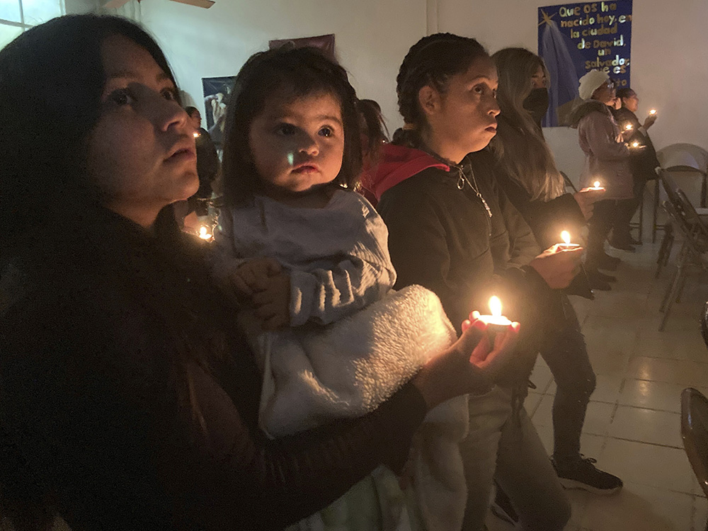 Guests at the Buen Samaritano shelter for migrants participate in a candle lighting ceremony in anticipation of Christmas in Ciudad Juárez, Mexico, across from El Paso, Texas, Dec. 22, 2022. (AP/Morgan Lee)