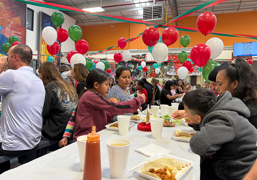 A migrant family enjoys a festive meal at the Kino Border Initiative headquarters in Nogales, Mexico, following a traditional posada procession along the border wall on Dec. 20. (Anita Snow)