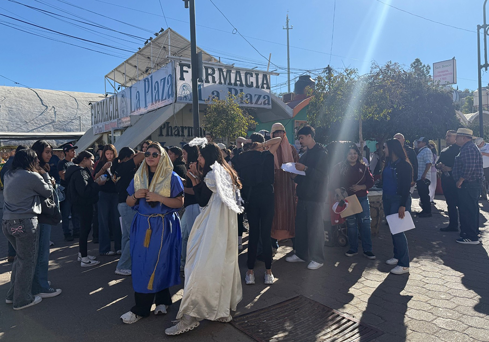 Teen girls in the foreground are dressed in costumes portraying Mary and an angel as they prepare Dec. 20 for a traditional yuletide procession known as a posada along the border wall in Nogales, Mexico. (Anita Snow)