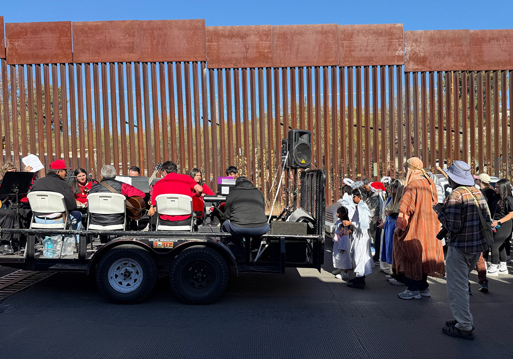 A lowbed trailer carrying musicians is towed by a truck along the U.S.-Mexico border wall during a posada procession in Nogales, Mexico, on Saturday, Dec. 20. (Anita Snow)