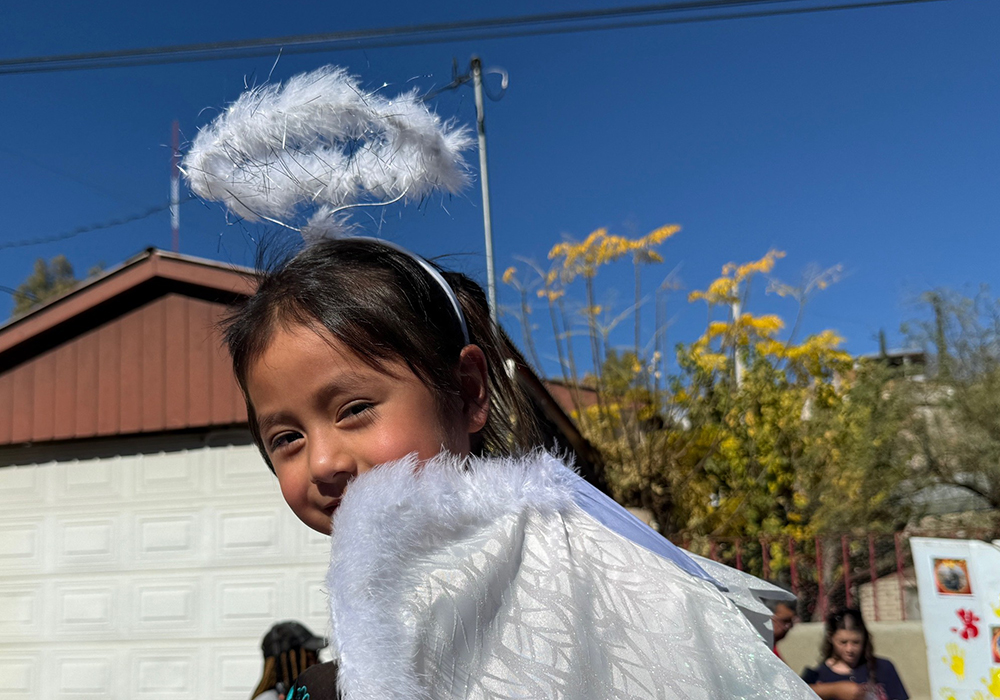 A little girl dressed as an angel and perched on the shoulders of a grown-up participates in a traditional posada procession along the border wall in Nogales, Mexico, on Saturday, Dec. 20. (Anita Snow)