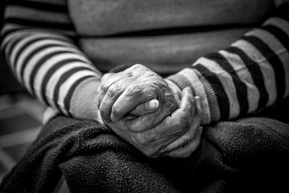 Elderly hands folded on a lap (Unsplash/Jorge Lopez)