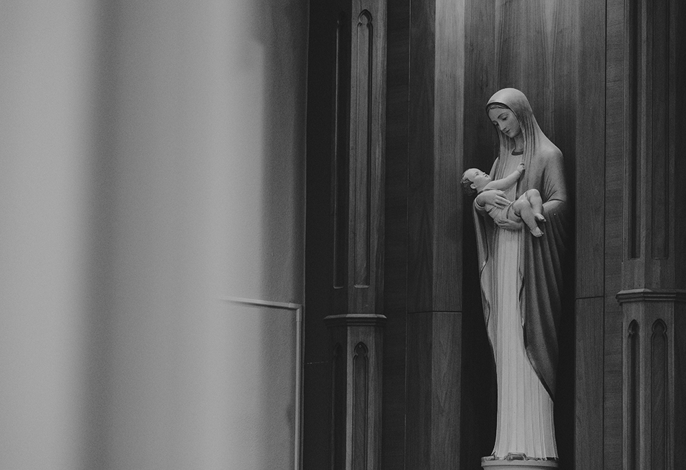 A black-and-white photo shows a statue of Mary cradling the infant Jesus. (Unsplash/Matea Gregg)
