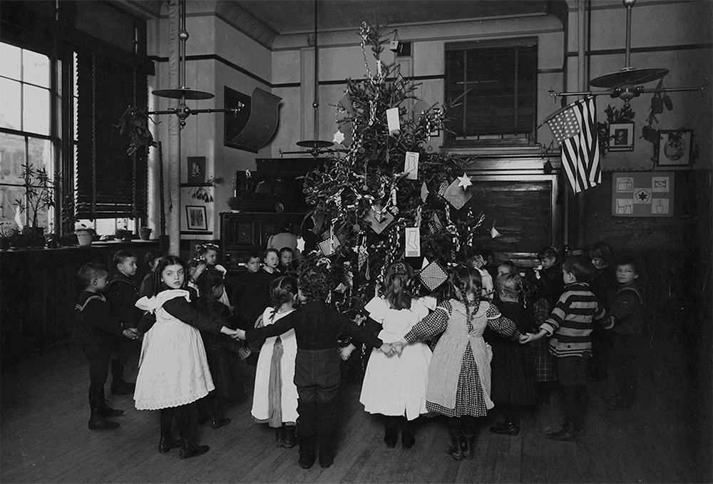 Children hold hands around a Christmas tree at a New York City school, circa 1900 (seligmanonline/The New York Public Library)