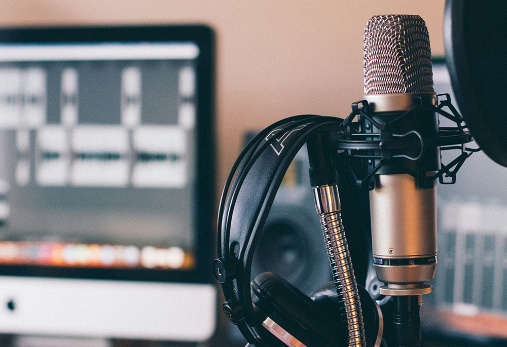 Headphones and a microphone are pictured in a studio setting. (Unsplash/Will Francis)
