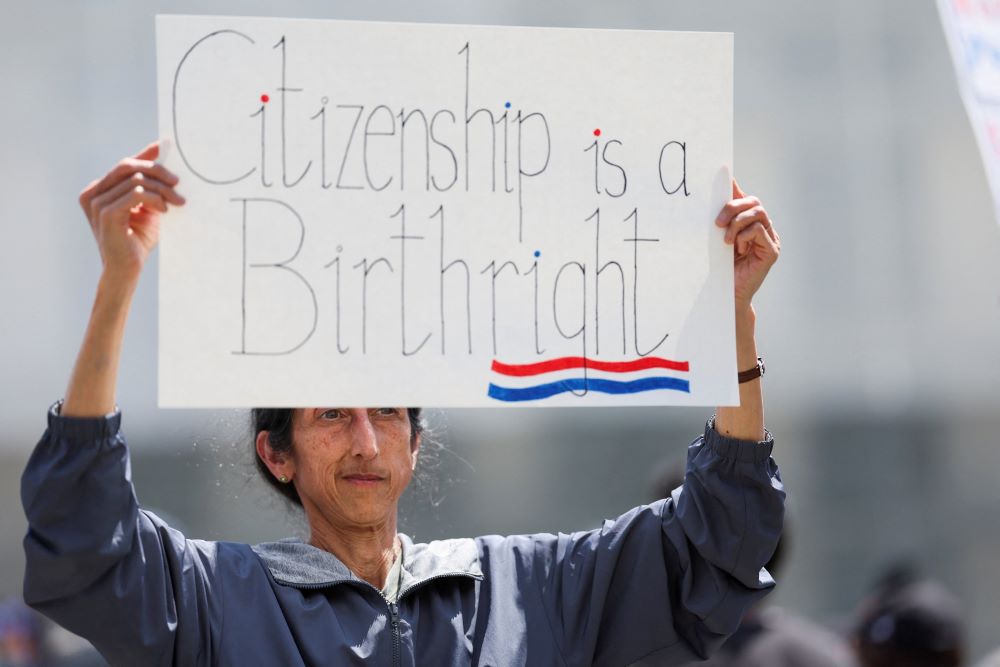 A demonstrator holds a sign as people protest on the day Supreme Court justices hear oral arguments over U.S. President Donald Trump's bid to broadly enforce his executive order to restrict automatic birthright citizenship, outside the U.S. Supreme Court in Washington May 15, 2025. (OSV News/Reuters/Leah Millis)