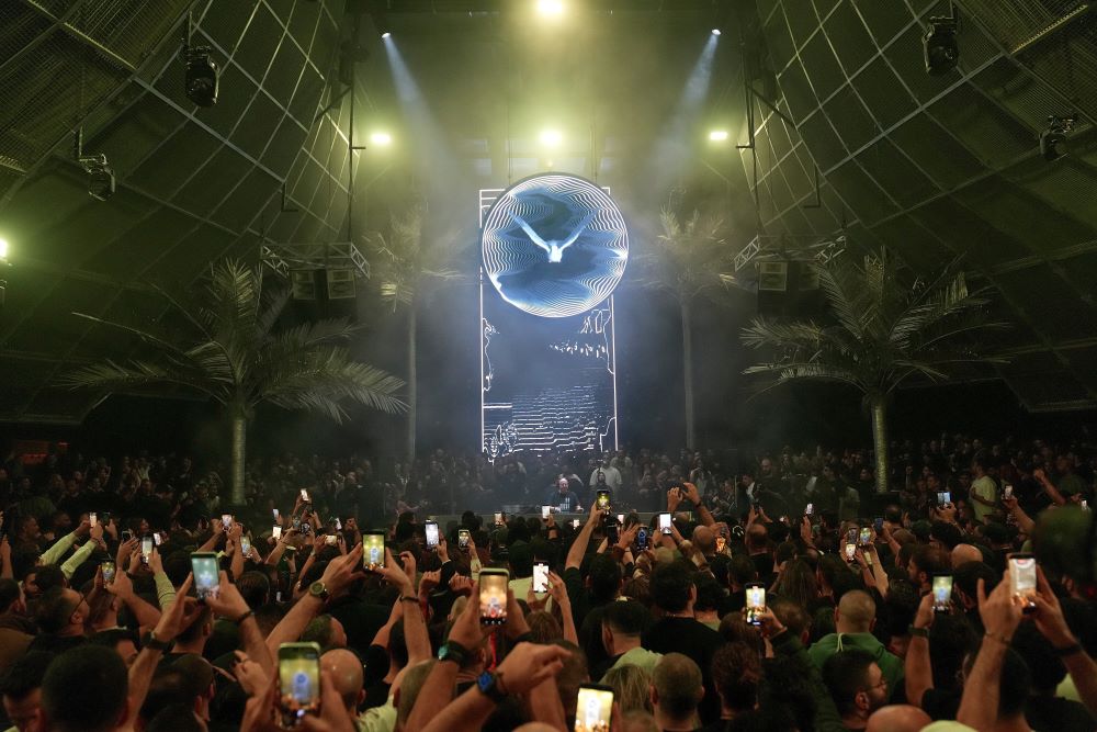 People at a crowded concert watch Fr. Guilherme Peixoto DJ a show in Beirut, Lebanon, Jan. 11. Reactions to his visit to Beirut were split on social media. (AP/Hussein Malla)