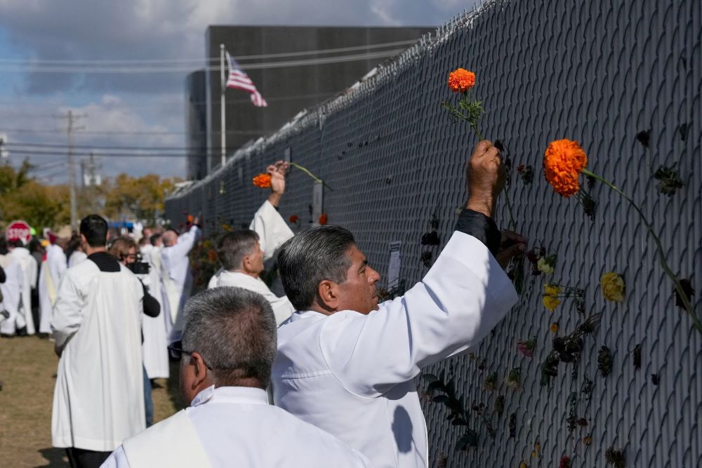 Religious leaders place marigold flowers used on the altar during the service into the fence surrounding the Broadview ICE facility in Chicago Nov. 1 on the day of an outdoor Mass observed by interfaith leaders, community members and volunteers. The Mass was led by Chicago Auxiliary Bishop José María Garcia-Maldonado. (OSV News/Reuters/Leah Millis)