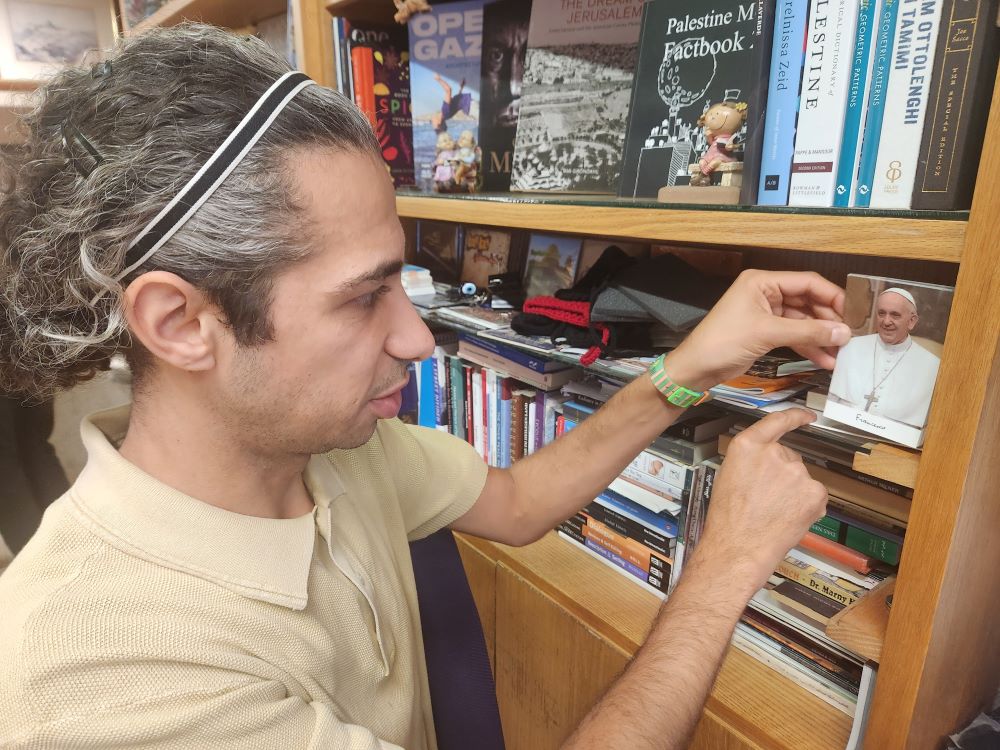 Ahmad Muna, assistant manager of the Educational Bookshop in east Jerusalem, points to a photo of the late Pope Francis he gave a place of honor at the shop. Muna, a non-observant secular Muslim, says Francis deserves a place of honor because of his commitment to Palestinian dignity. (NCR photo/Chris Herlinger)