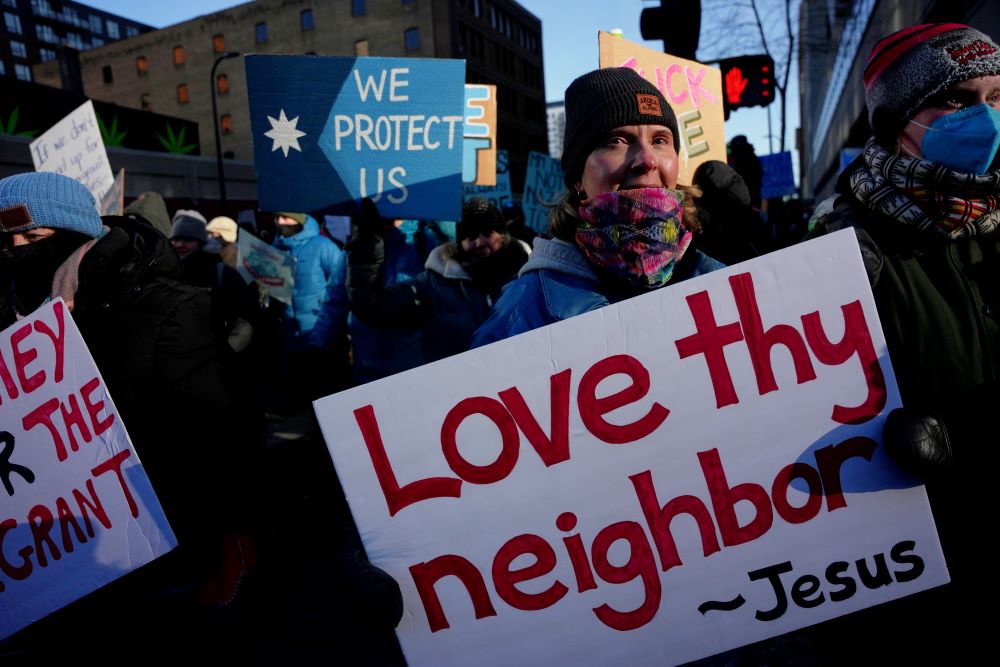 A protester holds a sign reading "Love thy neighbor — Jesus" during a rally against federal immigration enforcement on Friday, Jan. 23, 2026, in Minneapolis. (AP/Angelina Katsanis)