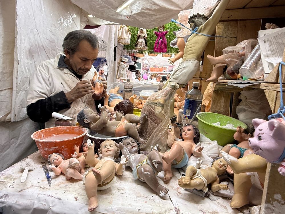 An artisan repairs a Baby Jesus figurine at a Mexico City market Jan. 27. Other damaged figurines await plaster and paint to prepare them for presentation at church on Candlemas, celebrated Feb. 2. (Anita Snow)