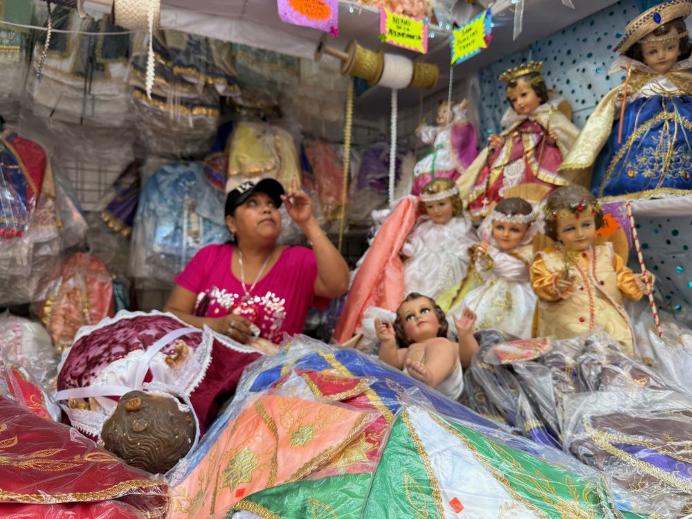 A vendor looks at some of the Baby Jesus figurines and outfits for sale Jan. 27 at a Mexico City market dedicated to preparing plaster dolls that represent the Christ Child for presentation at church on Candlemas, Feb. 2. (Anita Snow) 