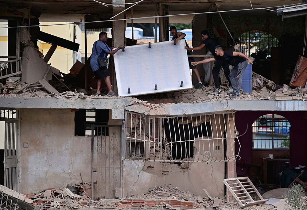 People carry personal belongings at a damaged building in Catia La Mar, Venezuela, Jan. 4, 2026, following U.S. strikes the previous day on Venezuela during which President Nicolás Maduro and his wife, Cilia Flores, were captured. (OSV News/Reuters/Gaby Oraa)