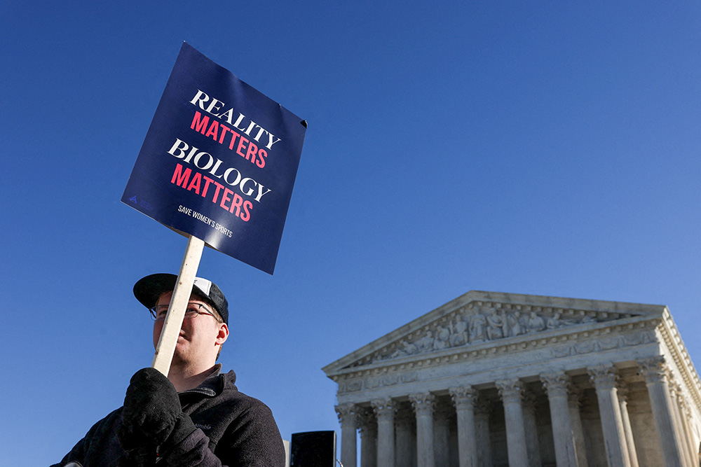 A supporter of keeping female sports based on biological sex holds a placard outside the U.S. Supreme Court in Washington Jan. 13, 2026, on the day justices heard oral arguments in two cases concerning efforts to enforce state laws banning transgender athletes from female sports teams at public schools. (OSV News/Reuters/Tyrone Siu)