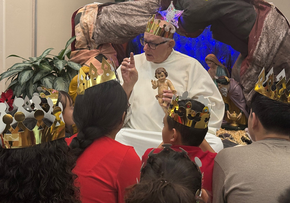 Fr. Raymond Riding, a Trinity missionary working in Tucson, Arizona, chats with migrant children about the baby Jesus during a Three Kings Day celebration on Jan. 4, 2026, telling them Christ's arms are always open to them. (Anita Snow)