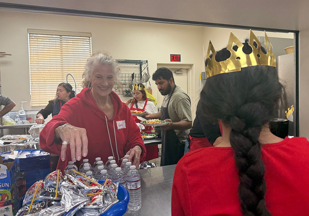 Volunteer Nancy Garcia serves water and a meal to a young migrant girl during a Three Kings Day celebration organized by Salvavision in Tucson, Arizona, on Jan. 4, 2026. (Anita Snow)