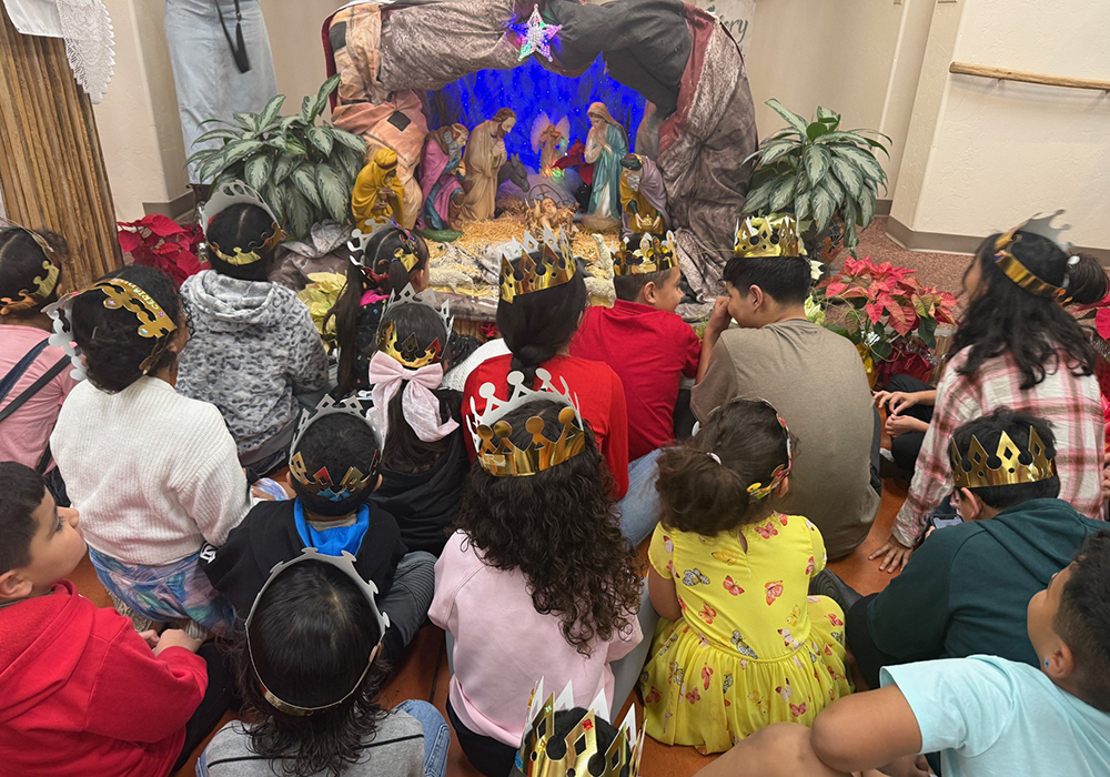 Migrant children wearing golden cardboard crowns gather around a large Nativity scene at a church where the advocacy group Salvavision organized a Three Kings Day celebration in Tucson, Arizona, on Sunday, Jan. 4, 2026. (Anita Snow)