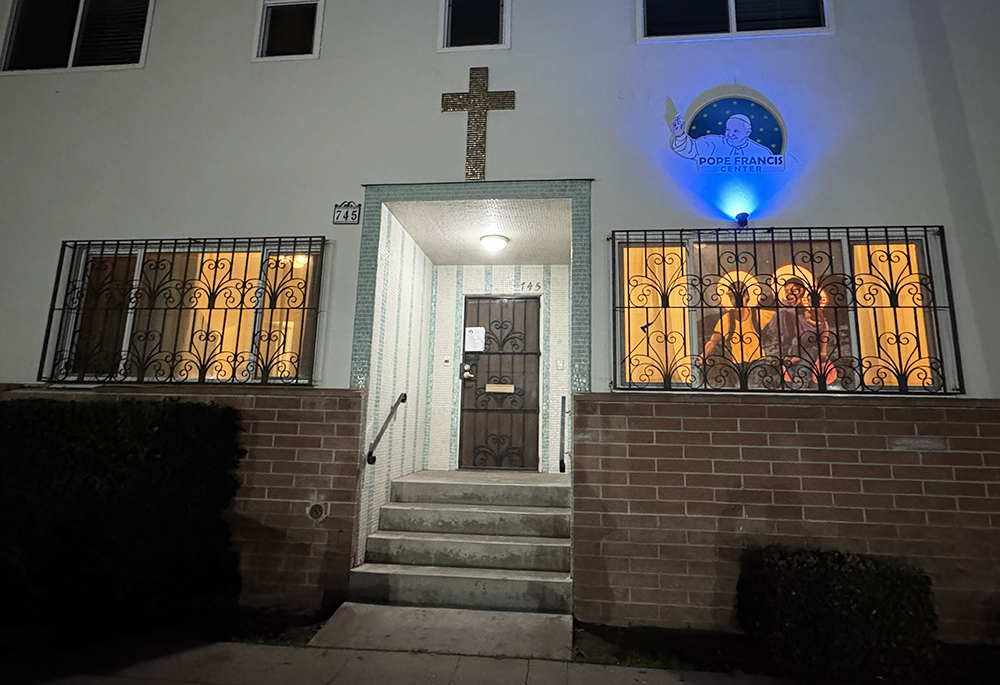 At the Pope Francis Center in San Diego, a depiction of the Holy Family as Latin American migrants hangs in the window, and a small spotlight shines on the smiling face of Pope Francis. (Anna Weaver)