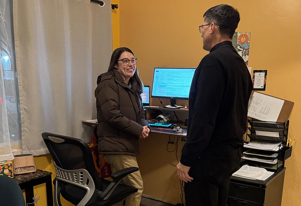 In the front office of the Pope Francis Center in San Diego, founding manager and navigator Brinkley Johnson speaks with Jesuit Fr. Scott Santarosa, the pastor of Our Lady of Guadalupe Parish, which operates the center. (Anna Weaver)