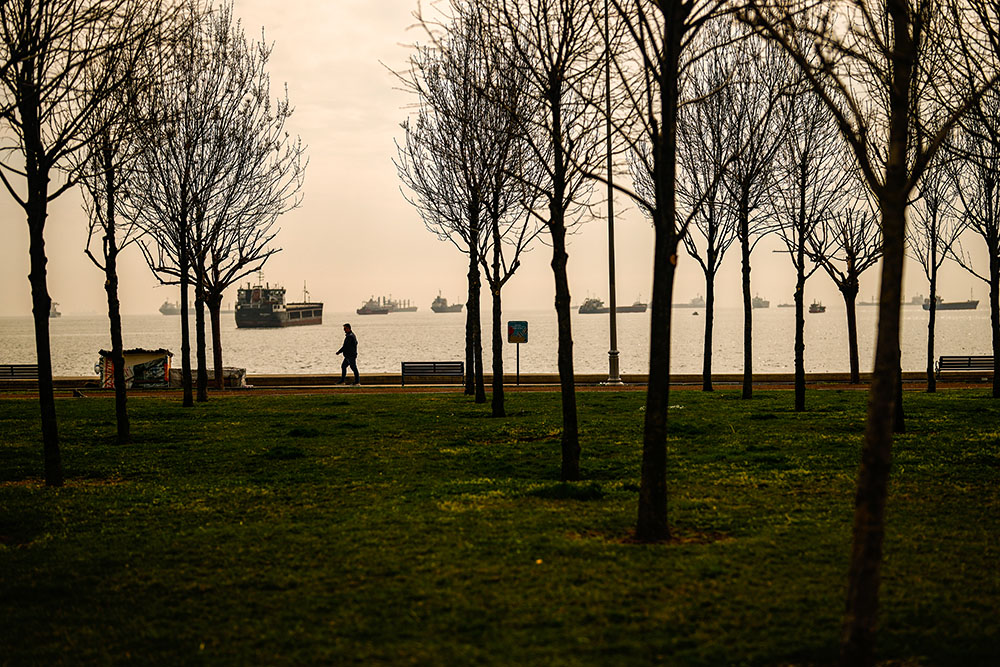 A man walks along a public park near cargo ships anchored in the Sea of Marmara, in Istanbul on March 16, 2024. (AP/Emrah Gurel)