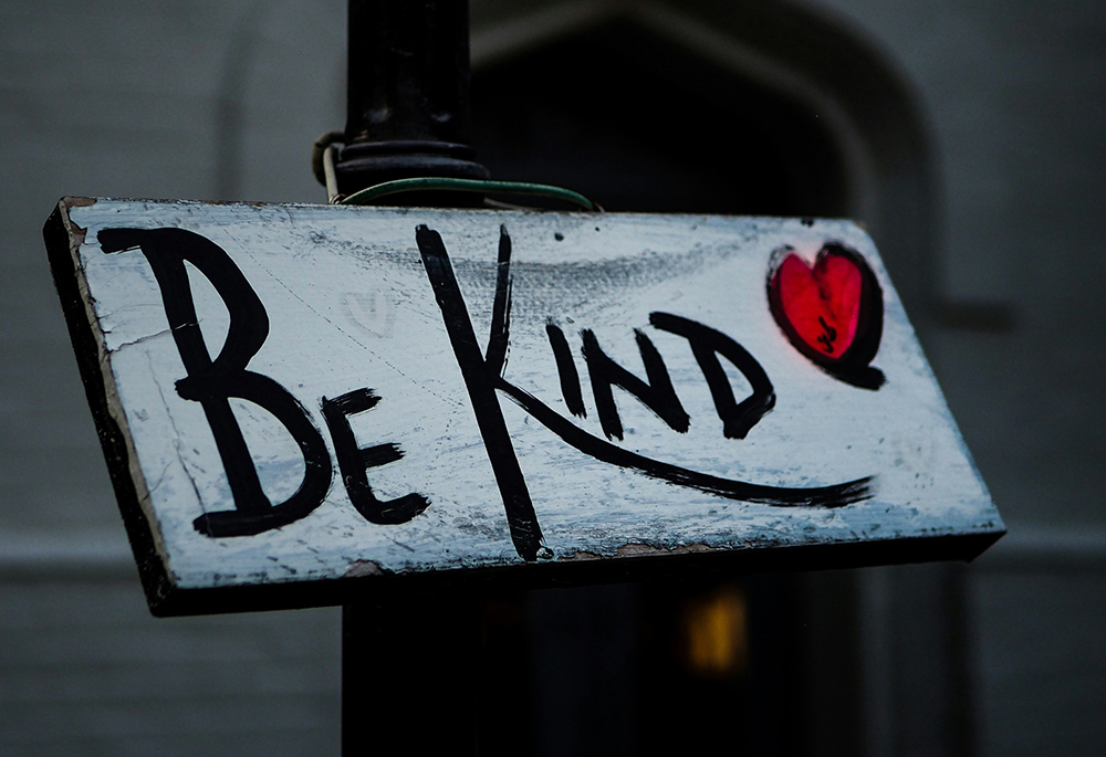 A sign reads "Be kind" in black text against a white background, with a red heart included on the right side. (Unsplash/Adam Nemeroff)