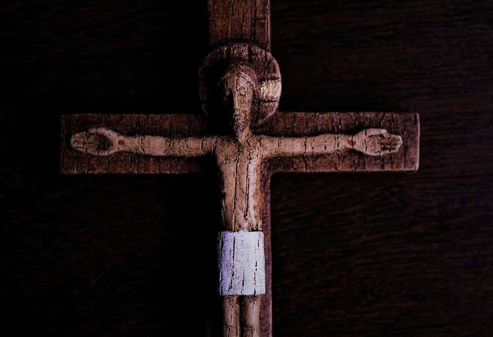 A weathered wooden crucifix against a dark background (Unsplash/Rui Silva, SJ)